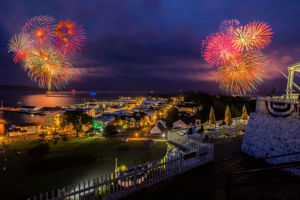 Fourth of July fireworks blast over Mackinac Island at night as seen from up on the bluff at Fort Mackinac