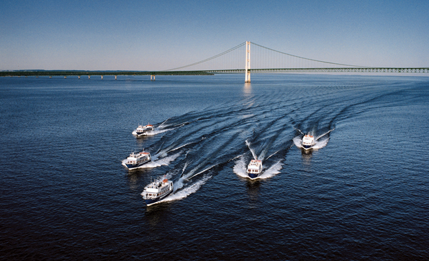 Five ferry boats cruise past the Mackinac Bridge on their way to Michigan’s Mackinac Island 