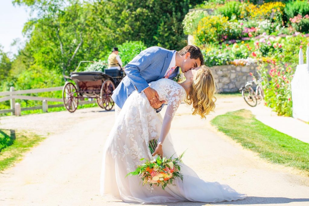 Newlywed Couple Kissing for Photo in Front of Horse-Drawn Carriage on Mackinac Island