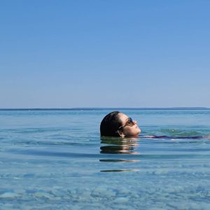A woman floats in shallow water off Mackinac Island with just her head above the surface