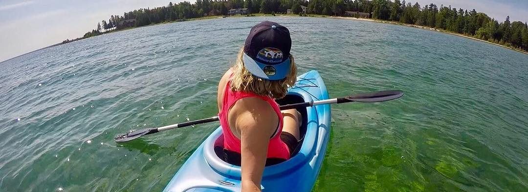 Woman Kayaking in Blue Kayak off the Coast of Mackinac Island