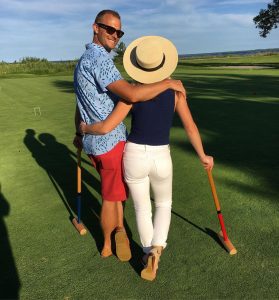 Man Looking Back for Photo While Enjoying a Game of Croquet With his Wife
