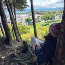 Hiker Relaxing Against a Tree in Woods Overlooking Downtown Mackinac Island 