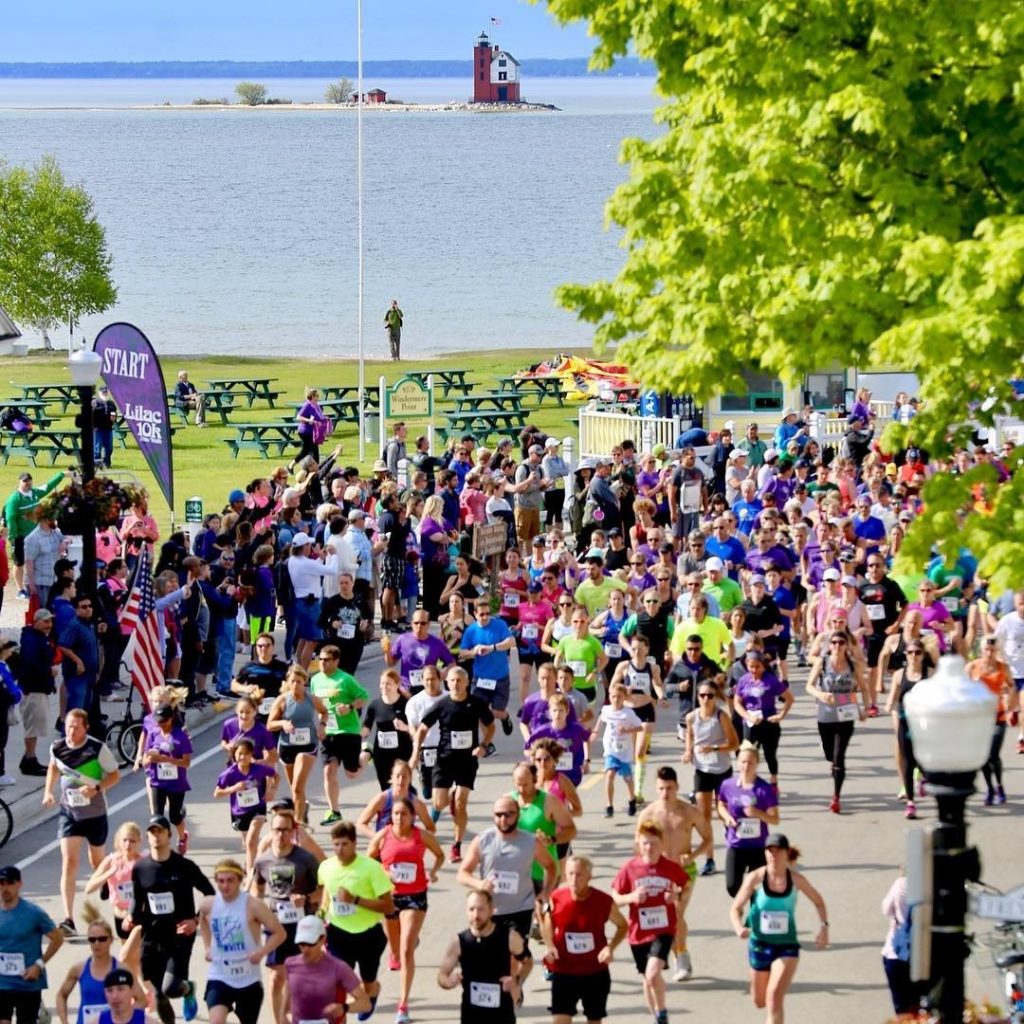 A crowd of runners leaves the starting line at one of Mackinac Island's scenic annual road races