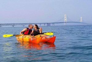 Couple Kissing While Paddling Side-by-Side in Kayaks in Waters Around Mackinac Island
