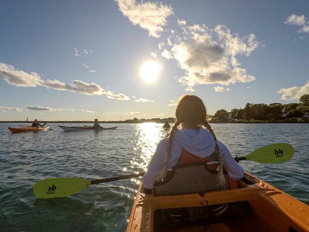 Girl with Pigtails Holding Paddle in Kayak in Front of Sun on Mackinac Island