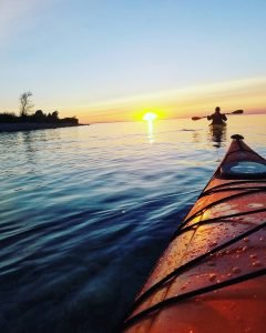 View from Kayaker Following Another Paddling Their Way Towards Sunset Off Mackinac Island