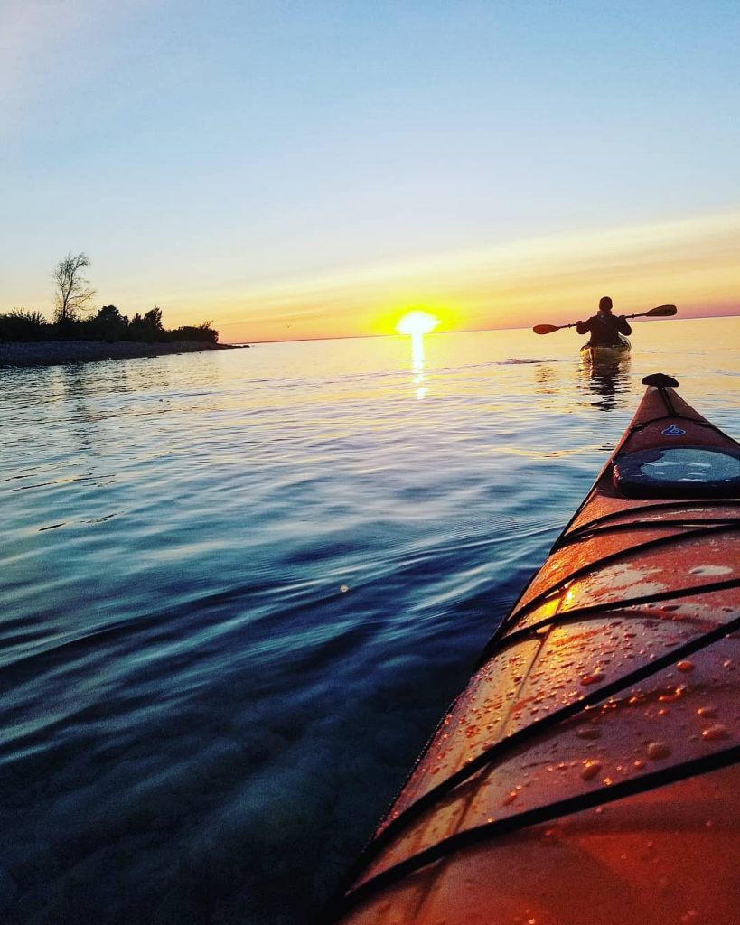 View from Kayaker Following Another Paddling Their Way Towards Sunset Off Mackinac Island