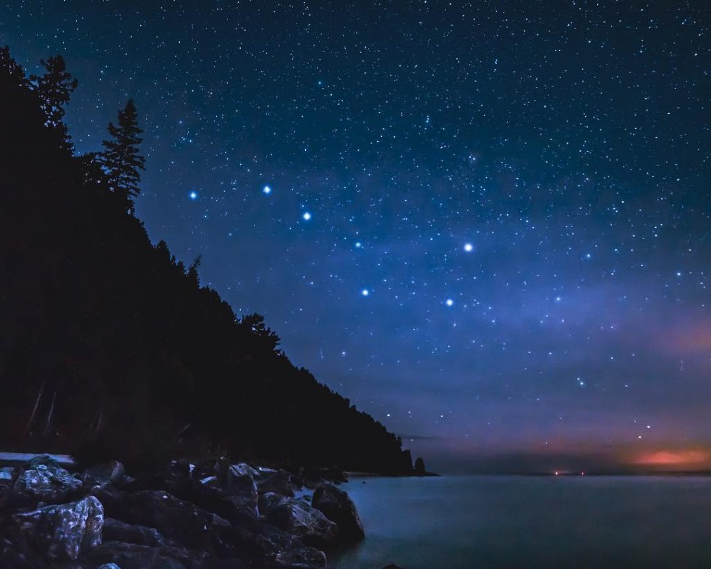 Stars sparkle in the night sky over the water off Mackinac Island