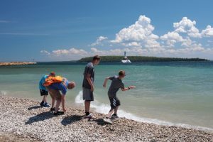 A family skips stones in the water at Mackinac Island’s Windermere Point.