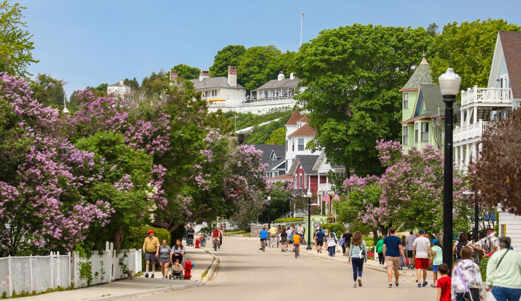 Visitors walk down Mackinac Island’s Main Street in June when it’s lined with blooming lilacs