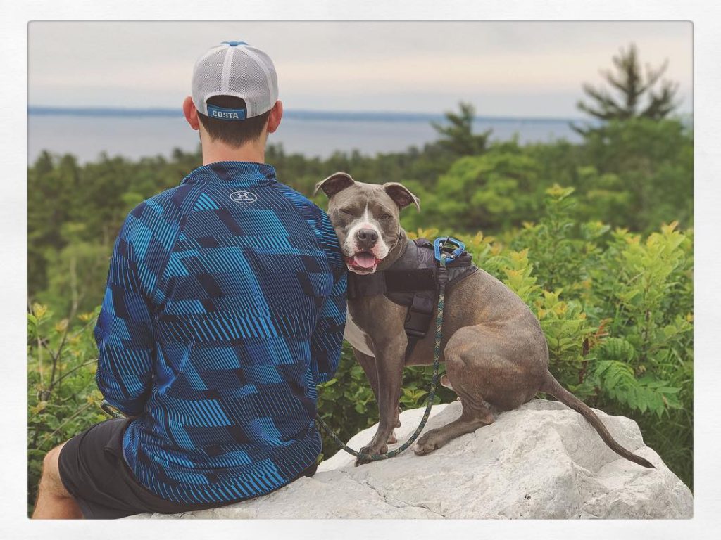 Dog Sitting on Rock with Owner – Mackinac Island Tourism Bureau