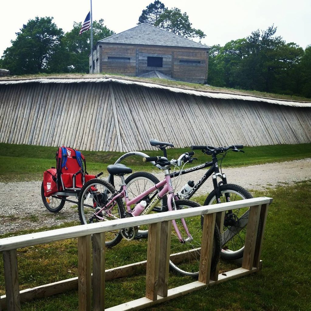 Two bicycles including one with a burley attached stand parked in a bike rack in front of Mackinac Island’s Fort Holmes