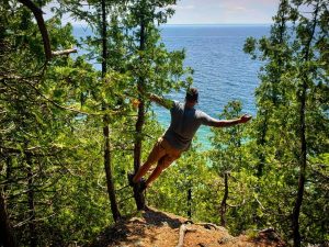 Man Swinging From Tree in Mackinac Island State Park Gazing at Horizon Surrounding Mackinac