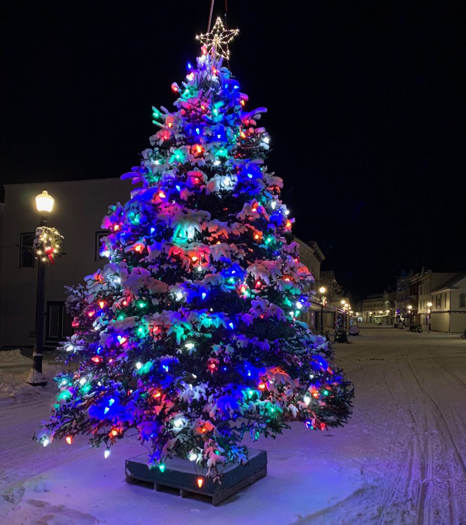 The Christmas tree in the middle of Main Street in downtown Mackinac Island is all lit up and covered in snow
