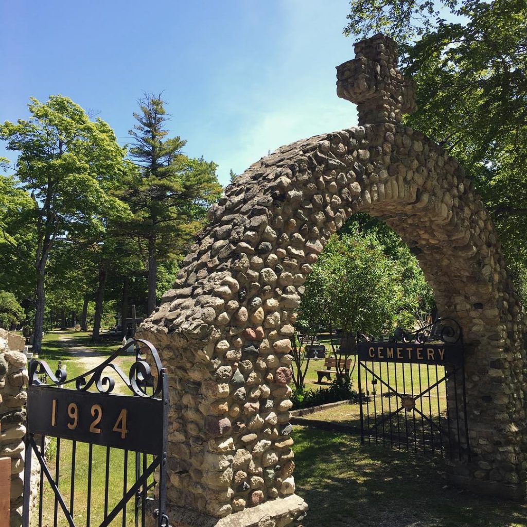 A stone arch and gate mark the entry to Ste. Anne's Cemetery on Mackinac Island