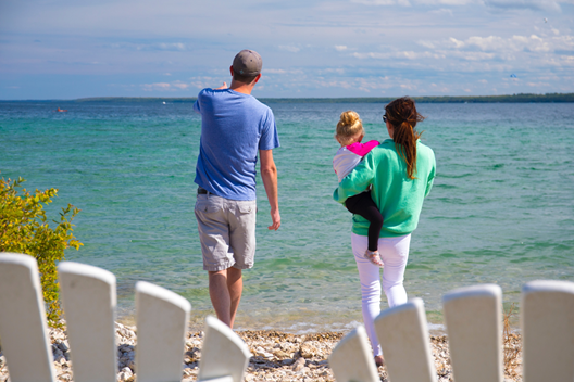 A family relaxes on the Mackinac Island waterfront with a pair of Adirondack chairs in the foreground.